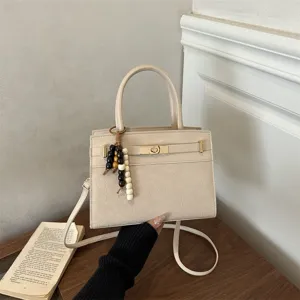 Schicke, strukturierte Handtasche in Beige mit elegantem Holzperlenanhänger und Schulterriemen.