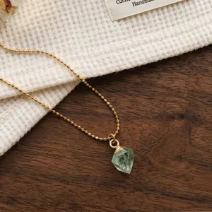 Delicate gold bead chain necklace with green crystal pendant, elegant clavicle chain detail.