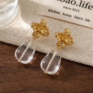 Primo piano dettagliato di lussuosi orecchini floreali dorati con cristalli a goccia trasparenti.
