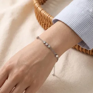 Close-up detail of a delicate silver double-layer chain bracelet with chic square charms.