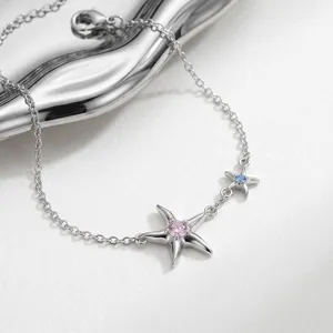 Close up of silver starfish chain bracelet featuring pink and blue crystal details.