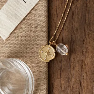 Gold compass coin and clear crystal pendant necklace detail shot, elegant jewelry for women