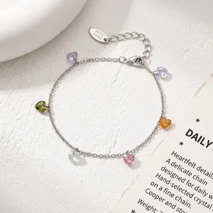 Close-up view of a delicate silver chain bracelet featuring colorful heart crystal charms and extension.