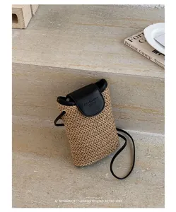 Vista detallada del elegante bolso cruzado mini de paja tejida con solapa de cuero negro.