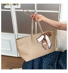 Vista dettagliata dell'elegante borsa beige con manici sottili e grazioso fiocco in nastro.