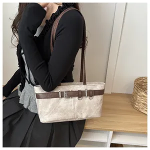 Vista detallada del bolso de hombro retro para mujer bajo el brazo con cinturon decorativo.
