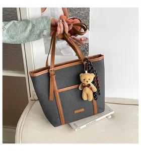 Vista detallada de un elegante bolso shopper gris tejido con detalles de cuero sintético marrón.