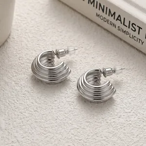Boucles d'oreilles créoles en C argentées à lignes multiples, détail de design.