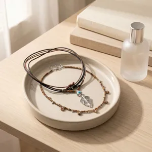 Bohemian layered leather cord and wooden bead necklace featuring a silver feather pendant on display.