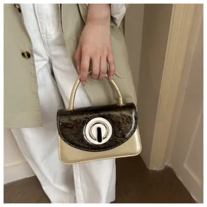 Stylish mini top-handle handbag with tortoiseshell flap and chic metallic gold body design.