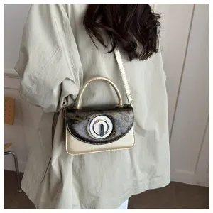 Detail view of a fashionable small metallic gold crossbody bag with unique round clasp for women.