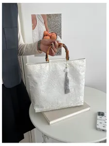 Vue détaillée du sac à main texturé blanc de style chinois avec poignée en bambou et gland.