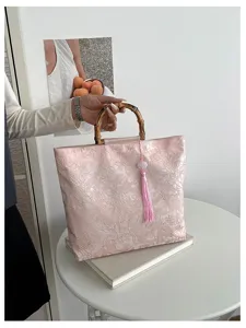 Sac à main rose fleuri de style chinois doté d'une poignée en bambou et d'un pompon.