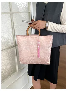 Détail du sac à main de style chinois, mettant en valeur la poignée bambou et le pompon.