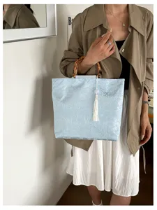 Sac à main en lin bleu clair style néo-chinois avec anses en bambou et élégant pompon blanc.