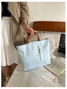 Sac à main style chinois moderne avec poignée en bambou, tissu jacquard et pendentif gland.