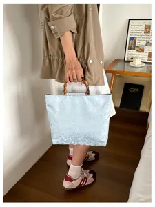 Vue détaillée du sac à main bleu clair en jacquard avec poignée en bambou texturée.