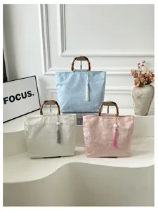 Sac a main en lin de style chinois avec poignee en bambou et pompon elegant pour soiree.