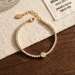 Detailed shot of a delicate gold-toned zircon bracelet with sparkling stones and a branded tag.