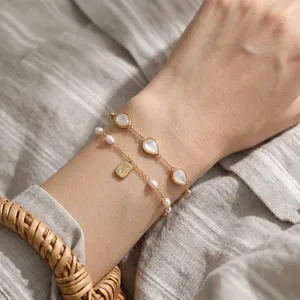 Close-up detail view of double-layer mother-of-pearl and pearl bracelet worn on wrist.