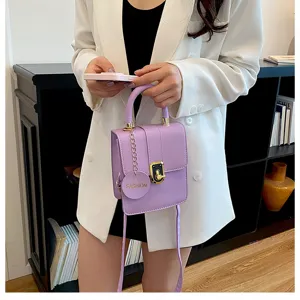 Gedetailleerd overzicht van de paarse mini crossbody tas met slot en handvat in dagelijks gebruik.