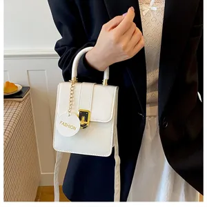 Detail opname van een stijlvolle witte mini handtas met ketting en metalen slot.