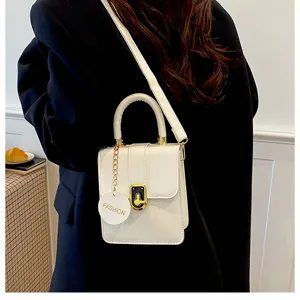 Detail witte schoudertas, chique kleine crossbody tas met gouden sluiting en ketting.