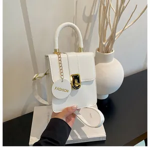 Gedetailleerd overzicht van witte minimalistische schoudertas met gouden slot en ketting.