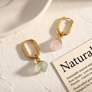 Detail view of asymmetrical raw crystal earrings with gold hoops, rose quartz and fluorite.