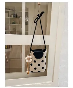 Minimalistische Umhängetasche aus Canvas mit Punkten, Klappe und süßem Blumenanhänger.