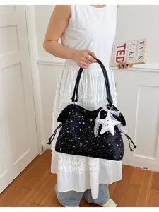 Detail shot of the star studded black tote bag with cute hanging pendant for women daily use.