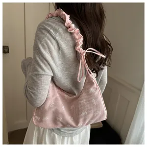 Detailed view of a cute pink gingham shoulder bag with white bows and stylish gathered strap.