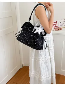 Detailed view of black star print tote bag with lace star pendant, worn by model for daily wear.