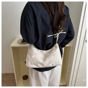 Detailed view of the cute beige plaid canvas shoulder bag featuring sweet white bow embroidery.
