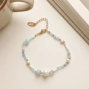 Delicate beaded detail showing handmade pearls, blue glass stones and gold charm hardware.