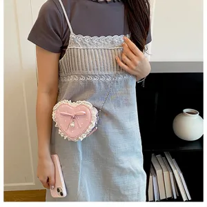 Detailed view of the pink heart-shaped crossbody bag with cute bow, lace trim and polka dot design.