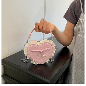 Detailed view of pink heart polka dot crossbody bag with cute lace trim and pearl bow charm.