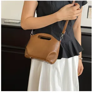 Vue détaillée du sac à main marron souple avec poignée découpée et fermoirs métalliques.
