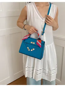 Bolso de hombro azul con estampado de avestruz, cierre de giro y pañuelo elegante.