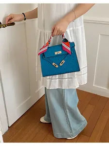 Vista detallada del elegante bolso de hombro azul con pañuelo y detalles dorados.