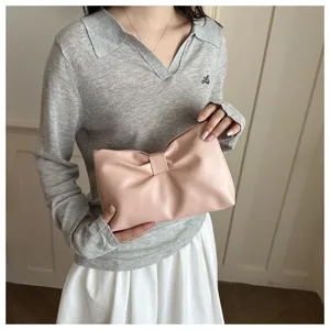 Vue détaillée d'une pochette rose plissée nœud nuage tenue par un modèle, accessorio élégant.