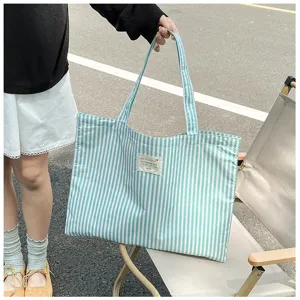 Detailansicht der Stoff-Tragetasche, lässige gestreifte Schultertasche mit Textiletikett.
