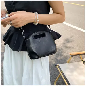 Détail de sac à main souple noir, élégant sac bandoulière avec poignée et quincaillerie en métal.