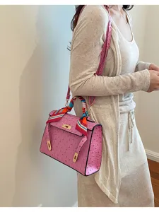 Detalle de primer plano del elegante bolso de hombro rosa con textura de avestruz y bufanda