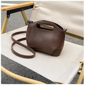 Detail de sac a main souple marron, sac bandou-liere vintage avec poignee et longue sangle.