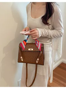 Bolso de hombro marrón con patrón de avestruz y pañuelo de seda, detalle elegante.