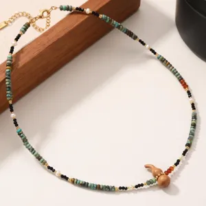 Detail shot of beaded necklace featuring turquoise stone beads and a cute wooden gourd pendant.