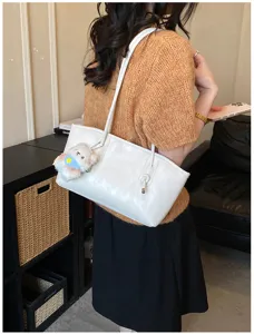 Elegant minimalist white shoulder bag for women, casual underarm tote with plush pendant.