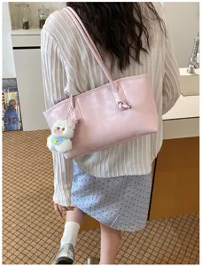 Detail view of the pink shoulder bag worn by model, featuring a cute plush bear pendant.