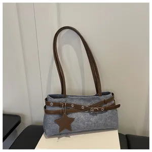 Detailed view of casual grey denim shoulder bag with brown leather straps and star charm.